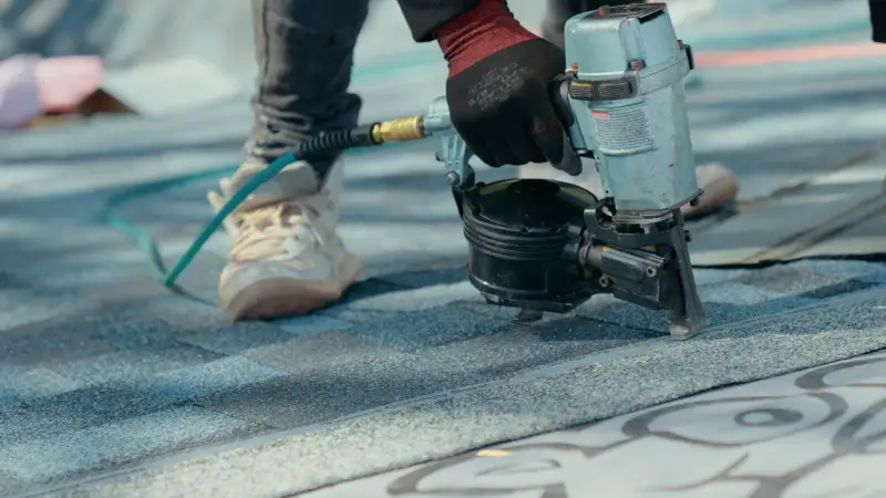 Roofing contractor using nail gun to repair shingles in Northeast Ohio