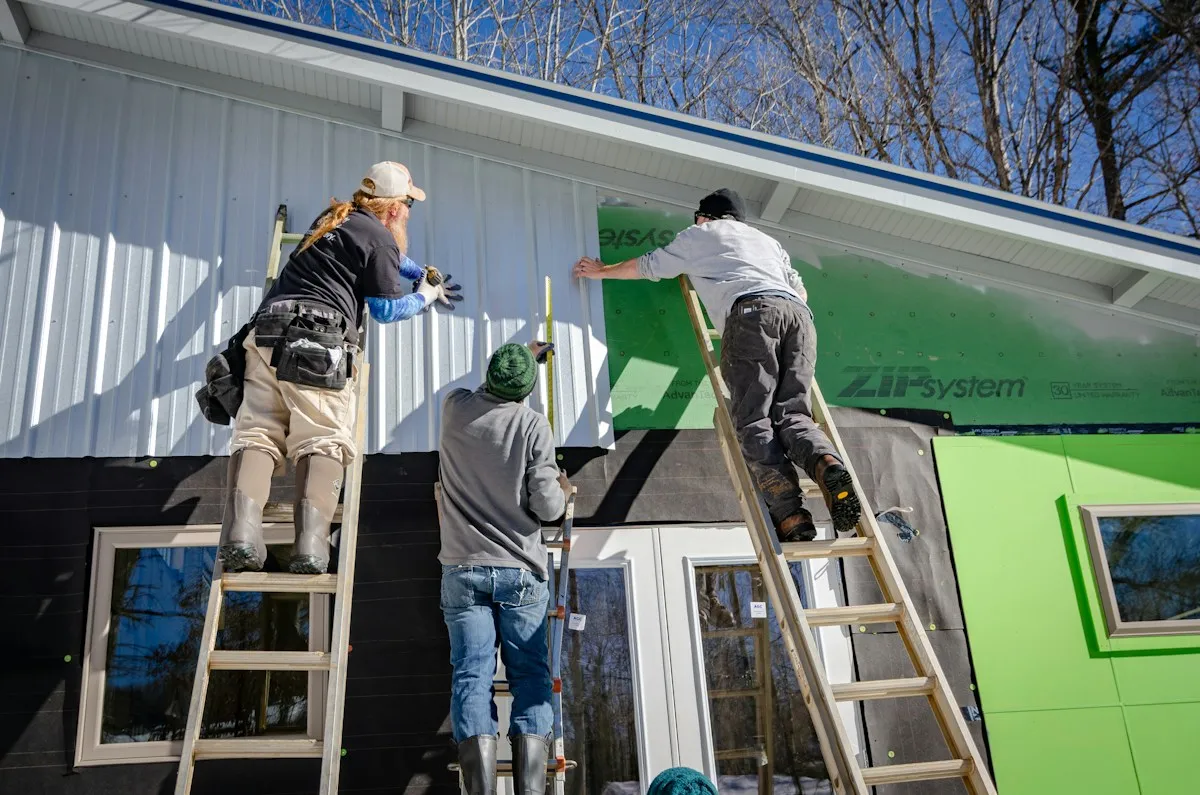 Crew on ladders installing new siding over house wrap on a home exterior